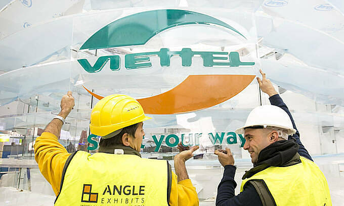 Two workers put up Viettel sign outside an office. Photo courtesy of Viettel.